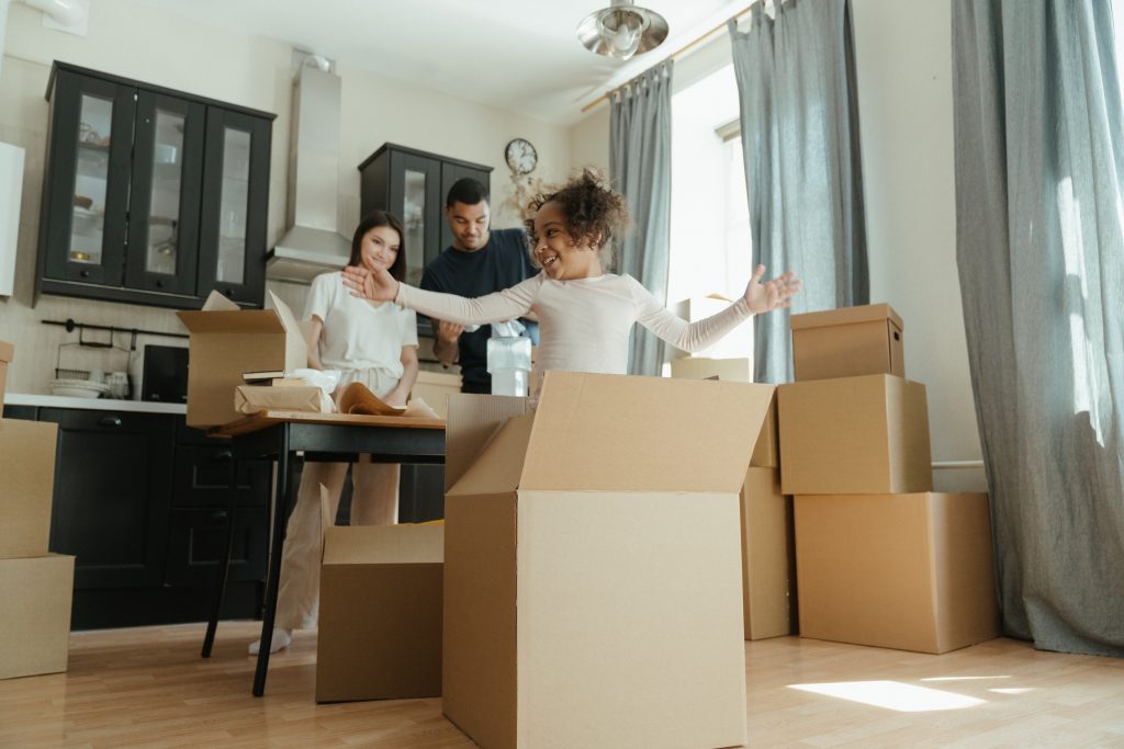 FHA loans. A young child coming out of a moving box, symbolizing the achievement of homeownership